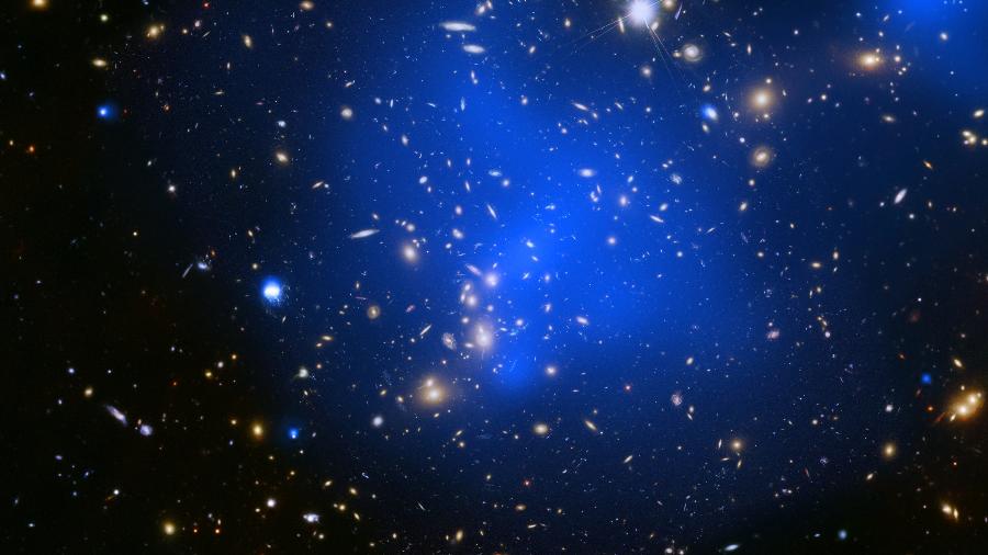 Aqui aparece o aglomerado de galáxias Abell 2744. Os aglomerados são os maiores objetos do Universo mantidos juntos pela gravidade e contêm enormes quantidades de gás superaquecido (com temperaturas de dezenas de milhões de graus), que brilham intensamente nos raios-X - Divulgação/Nasa