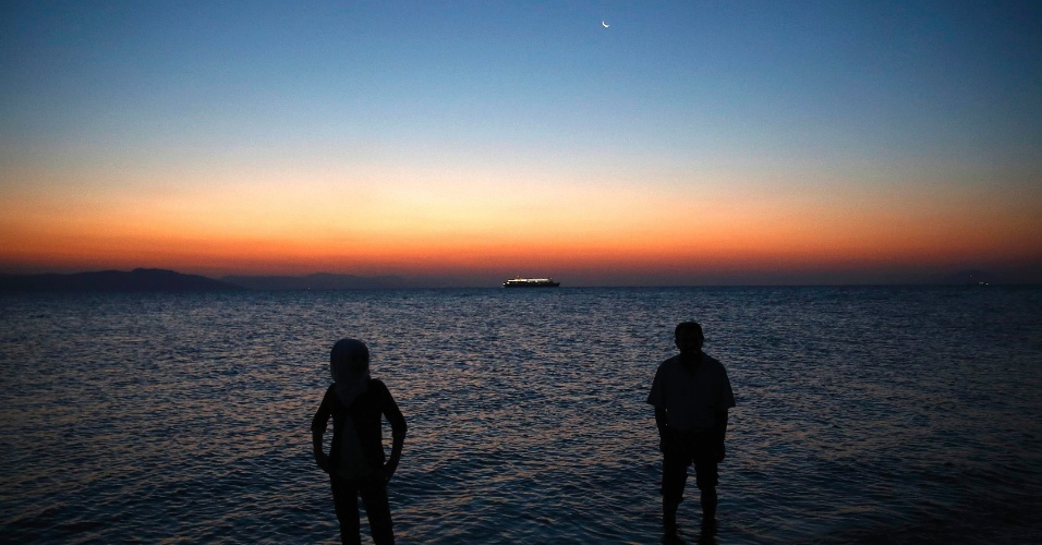 12.ago.2015 - Refugiados sírios ficam em frente ao mar após chegarem a uma praia na ilha grega de Kos, na Grécia