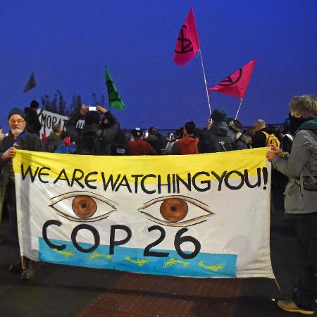 Manifestantes do Extinction Rebellion exibem faixa com a mensagem "Estamos de olho em vocês", em protesto durante a COP26 - ANDY BUCHANAN / AFP