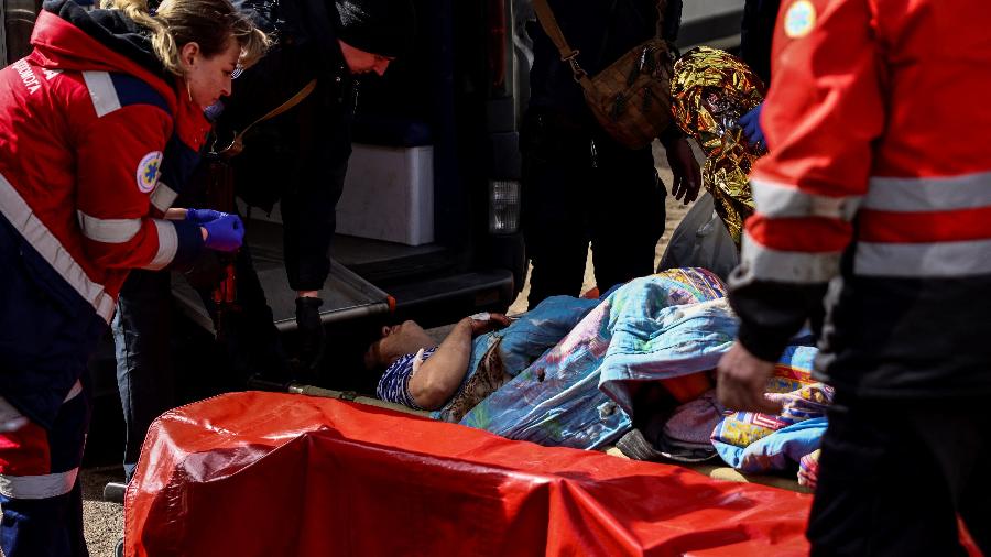 28.mar.2022/ Uma mulher ferida é socorrida por equipes de resgate ao chegar a Kiev depois de fugir de sua casa nos arredores da cidade. - RONALDO SCHEMIDT / AFP