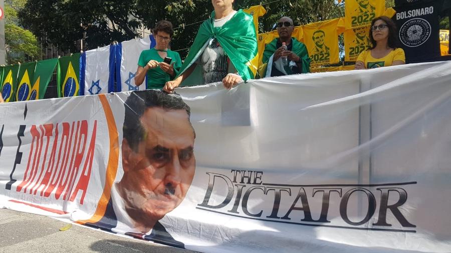 Manifestante a favor do presidente Jair Bolsonaro segura faixa que chama ministro Luís Roberto Barroso de "ditador", em inglês - José Dacau/UOL