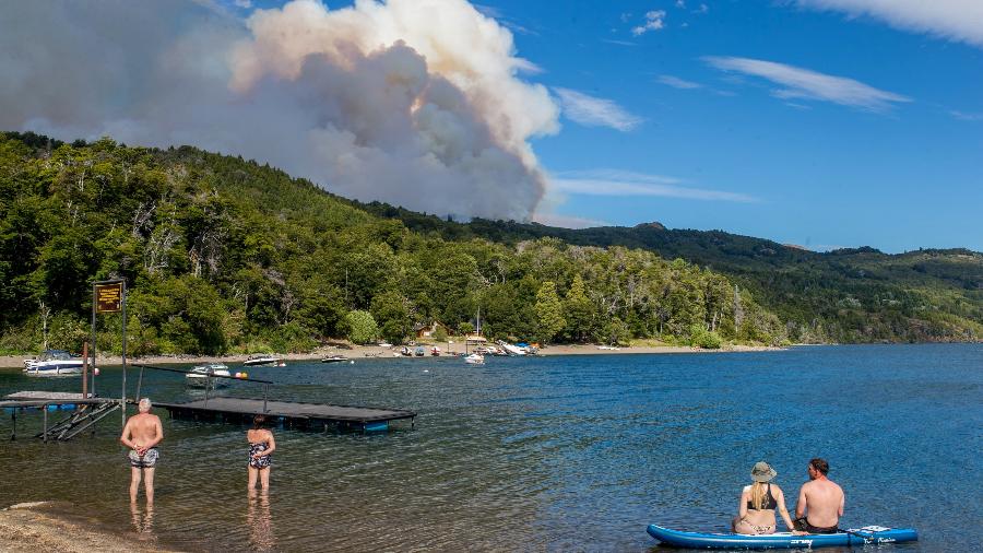 Turistas olhando para uma nuvem de fumaça de um incêndio florestal no Parque Nacional Los Alerces, na província de Chubut, Argentina, em 28 de janeiro de 2024