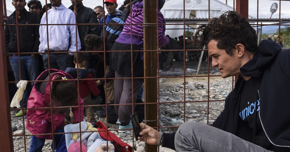 28.set.2015 - O ator britânico Orlando Bloom, embaixador da Boa Vontade do Unicef, fotografa criança em visita a campo de refugiados em Gevgelija, Macedônia
