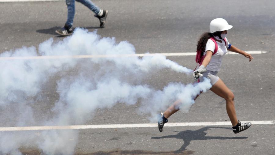 1º.mai.2019 - Um apoiador da oposição corre com uma bomba de gás lacrimogêneo durante comício contra o governo do presidente da Venezuela, Nicolas Maduro - Reuters/Ueslei Marcelino