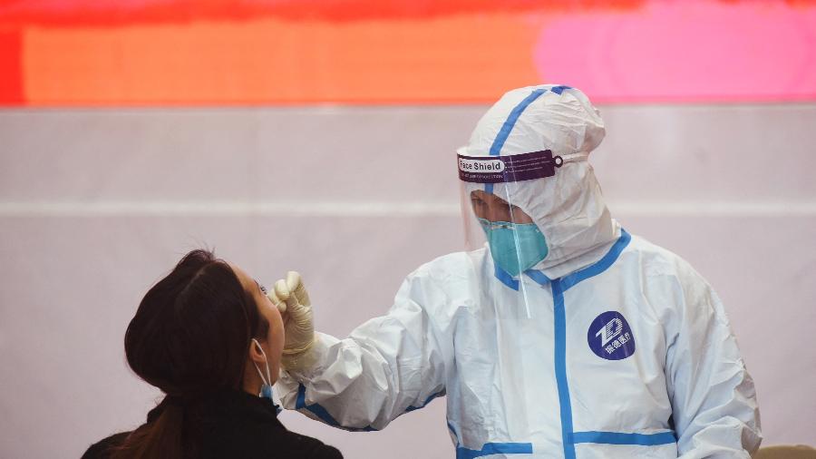 15.dez.2021 - Trabalhador da saúde realize teste de covid-19 em mulher em Hangzhou, na China - AFP