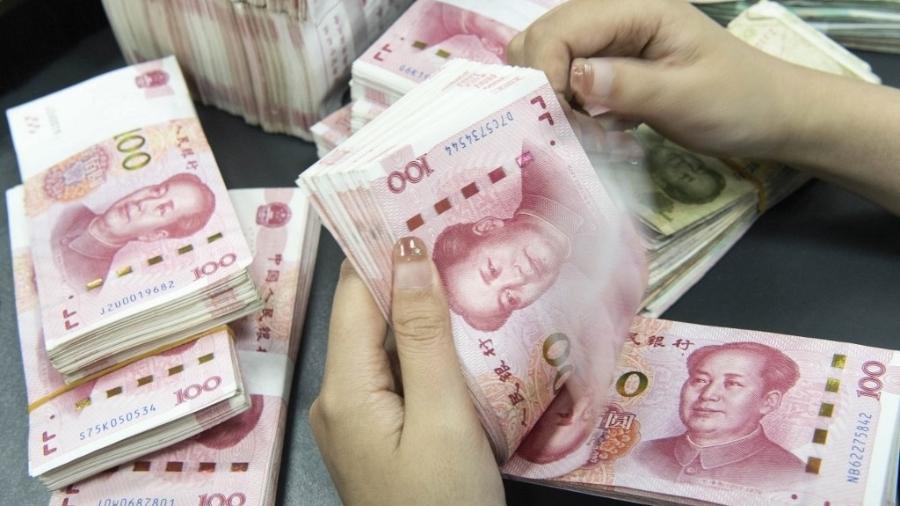Pessoa conta notas de 100 yuans na China - Divulgação via AFP