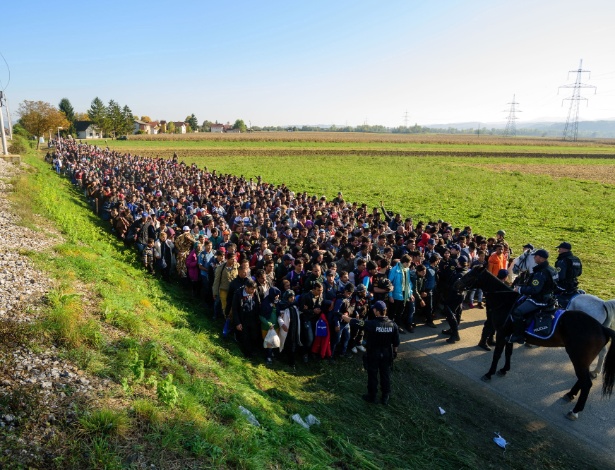 24.out.2015 - Policiais escoltam migrantes e requerentes de asilo até um centro de refugiados, após terem cruzado a fronteira croato-eslovena perto de Rigonce (Eslovênia) - Jure Makovec/AFP