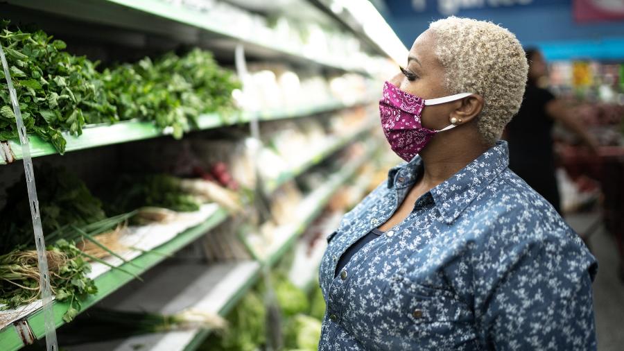Mulher faz compras em supermercado, usando máscara para se proteger do coronavírus - Getty Images