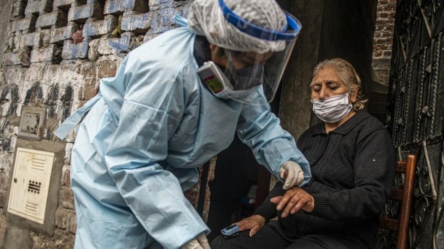 Funcionária do Ministério da Saúde testa paciente idosa para covid-19 em Santa Anita, no Peru - Ernesto Benavides/AFP