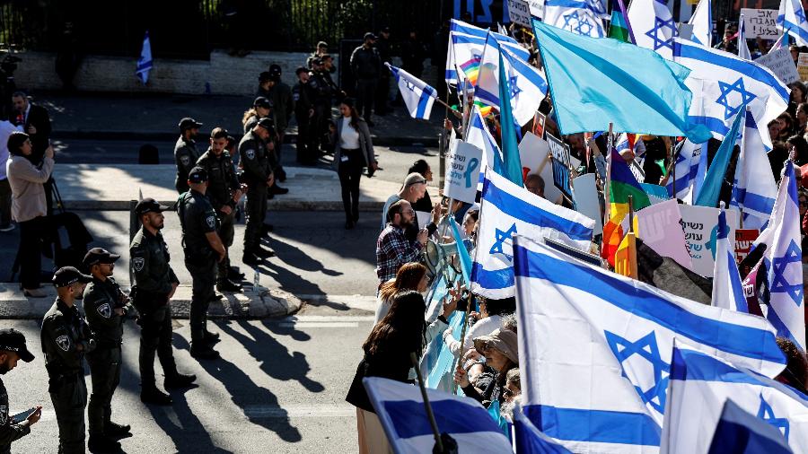 29.dez.22 - Pessoas seguram cartazes e bandeiras enquanto protestam do lado de fora do Knesset, o parlamento de Israel, no dia em que o novo governo de direita é empossado, com Benjamin Netanyahu como primeiro-ministro, em Jerusalém - AMMAR AWAD/REUTERS