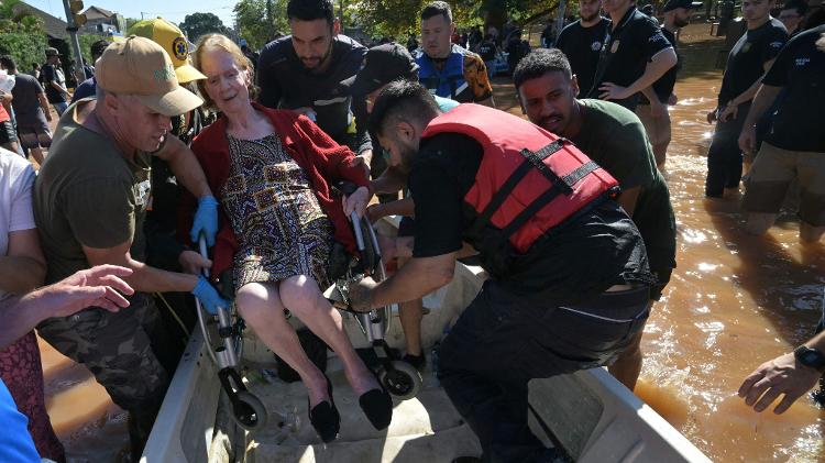 Grupo de resgate ajuda mulher em cadeira de rodas a subir no barco