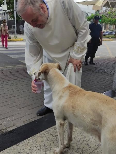 Padre João Paulo Araújo Gomes dá água para cachorro que apareceu na igreja