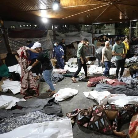 Pessoas se reúnem em torno de corpos de palestinos mortos em um ataque ao Hospital Al-Ahli Arab