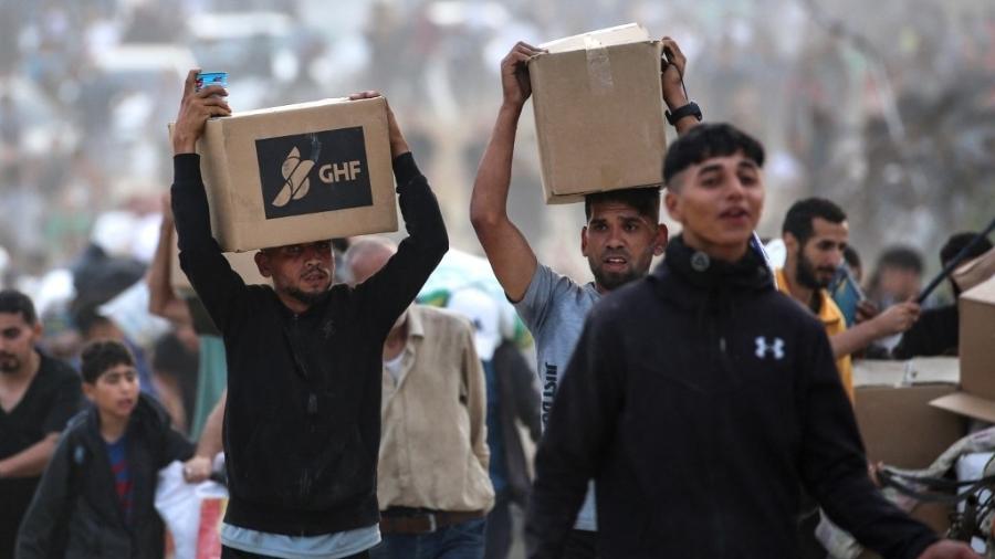 8.jun.2025 - Palestinos carregam doações da GHF (Fundação Humanitária de Gaza), grupo de ajuda privado apoiado pelos EUA 8.jun.2025 - Palestinos carregam doações da GHF (Fundação Humanitária de Gaza), grupo de ajuda privado apoiado pelos EUA