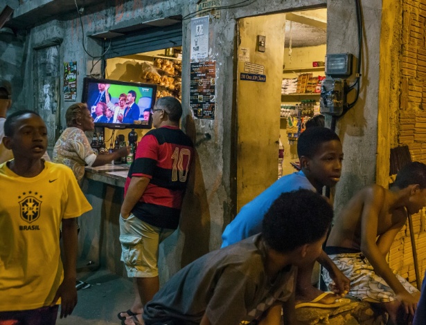 A cerimônia de abertura da Olimpíada é vista em TV de um bar na Mangueira, no Rio - Mauricio Lima/The New York Times
