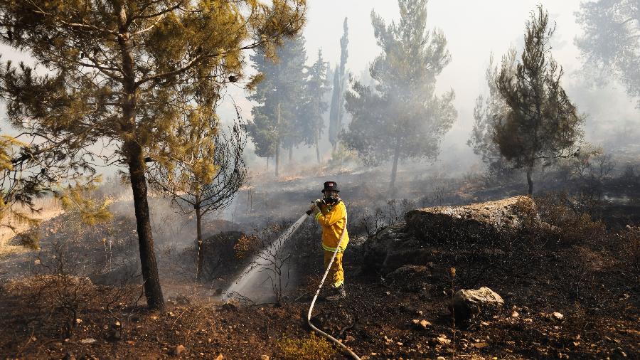 09.jun.2021 - Bombeiro ajuda a apagar um incêndio perto do Kibutz Maale Hahamisha em Israel, nos arredores de Jerusalém - REUTERS / Ronen Zvulun