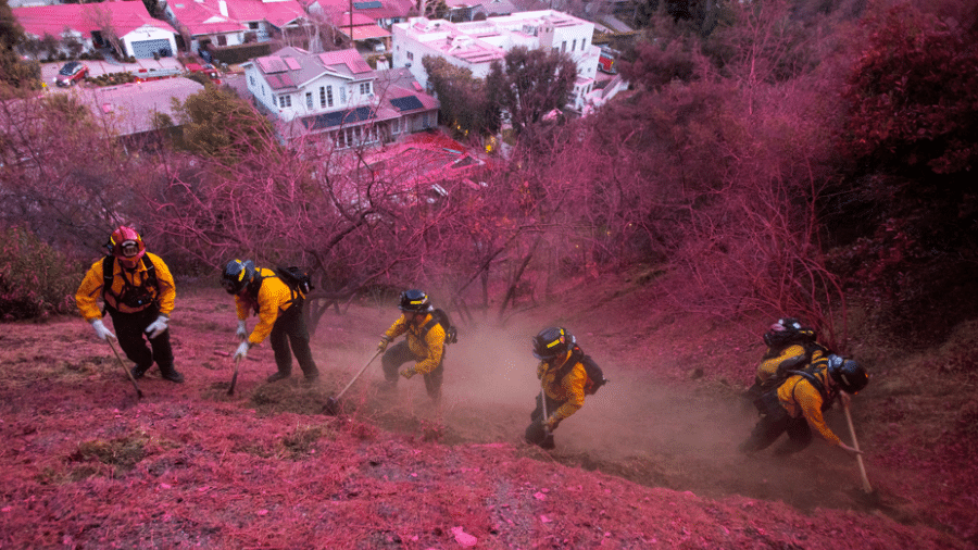 Em Los Angeles, brigadistas trabalham em bairros como Mandeville Canyon na limpeza do retardante de incêndios despejado sobre diferentes pontos da região - Ringo Chiu / Reuters