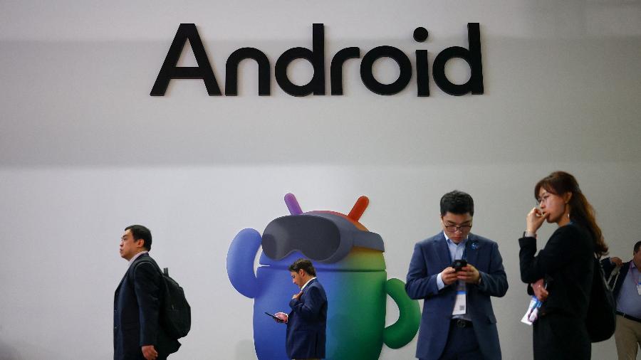 Visitantes do MWC 2026 passam por logotipo e mascote do sistema Android, do Google Visitantes do MWC 2026 passam por logotipo e mascote do sistema Android, do Google