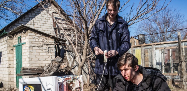 Aleksandr Kryukov (esquerda) observa Pavel Pavlov usar o microondas para gerar faíscas em Luhansk, na Ucrânia - Brendan Hoffman/The New York Times