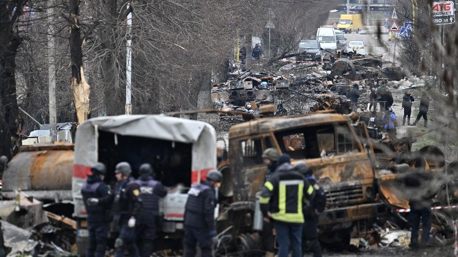 05.abr.2022 - Engenheiros de campo do Serviço de Emergência do Estado da Ucrânia realizam limpeza de minas entre veículos destruídos em uma rua de Bucha - GENYA SAVILOV / AFP