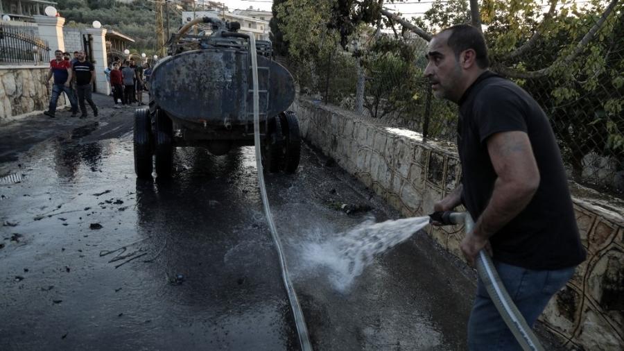 Homem limpa área de ataque na vila libanesa de Shehabiya