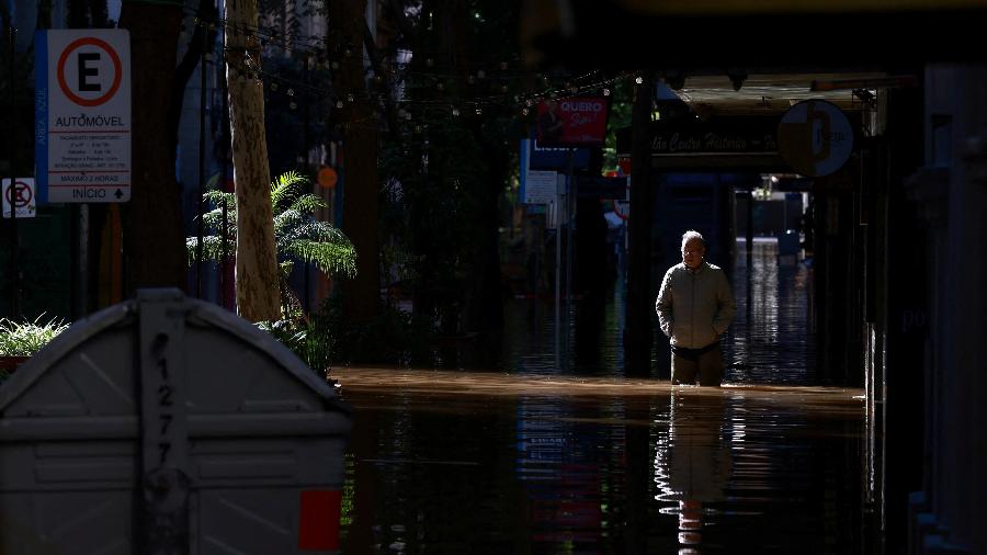 15/05/2024 - Homem caminha pelo centro histórico de Porto Alegre com água até os joelhos
