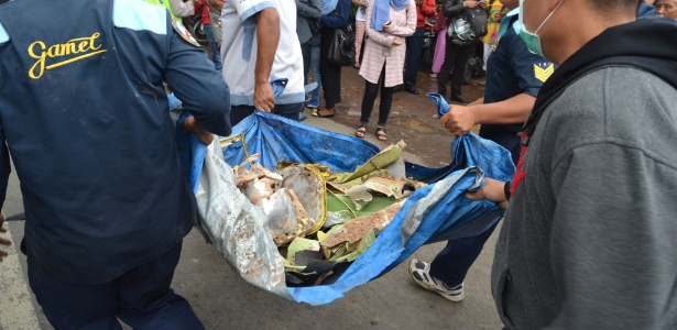 Equipes de resgate carregam destroços de Super Tucano que caiu em área residencial em Malang, na Indonésia - Aman Rochman/AFP