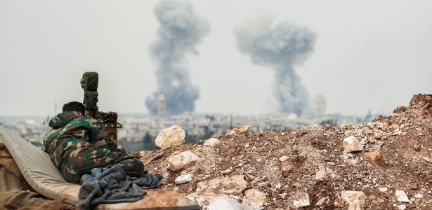 Atirador das forças sírias observa a fumaça no horizonte próximo à cidade de Qumhanah no interior da província de Hama - AFP
