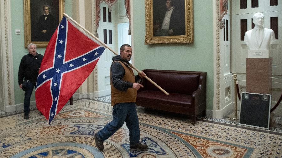 Apoiador do presidente Donald Trump invadiu o Capitólio carregando uma bandeira confederada - Saul Loeb/AFP