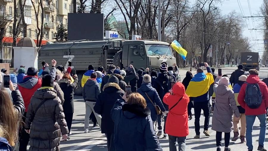 20.mar.22 - Manifestantes, alguns exibindo bandeiras ucranianas, cantam "vá para casa" enquanto caminham em direção a veículos militares russos em retirada na cidade de Kherson, Ucrânia - HANDOUT/VIA REUTERS