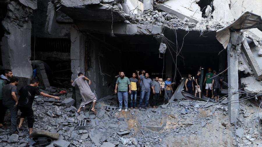 Civis palestinos procuram sobreviventes nos escombros de um edifício atingido durante o bombardeio israelense em Khan Yunis, no sul da Faixa de Gaza