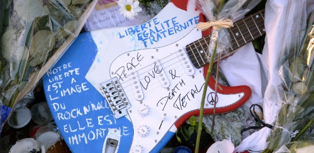 Guitarra com mensagens de liberdade e paz é colocada na porta do Bataclan, um dos locais atacados em Paris em novembro - B. Guay/AFP