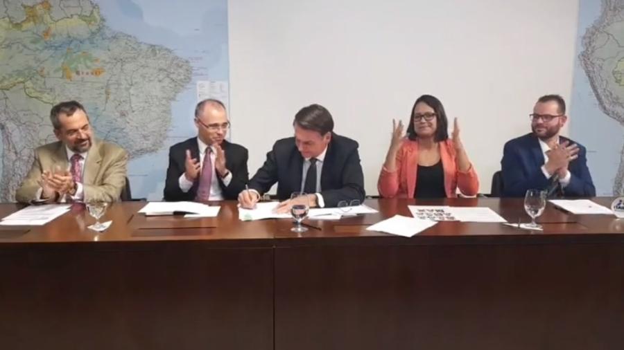 25.abr.2019 - Presidente Jair Bolsonaro assina parecer da AGU ao lado do advogado-geral da União, André Luiz Mendonça - Reprodução