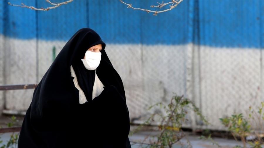 Uma mulher usando uma máscara caminha na rua em Teerã no dia 2 de março de 2020 - AFP