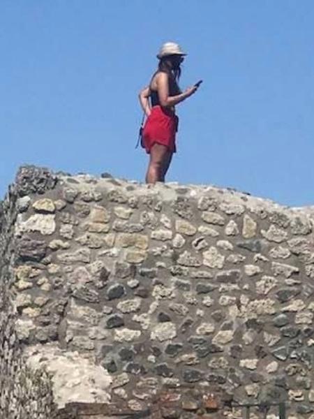 Turista ignorou placas que impedem de encostar ou subir em ruínas de mais de 2 mil anos na Pompeia, na Itália - Reprodução/Facebook
