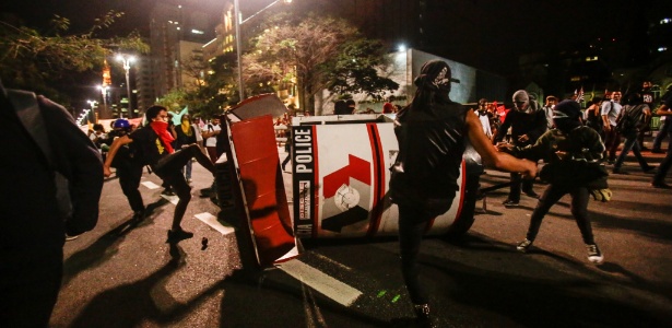 Um grupo adepto da tática black bloc vira uma base da Polícia Militar na Avenida Paulista, em São Paulo, nesta segunda-feira (13), durante protesto contra a redução da maioridade penal - Gabriela Biló/Estadão Conteúdo