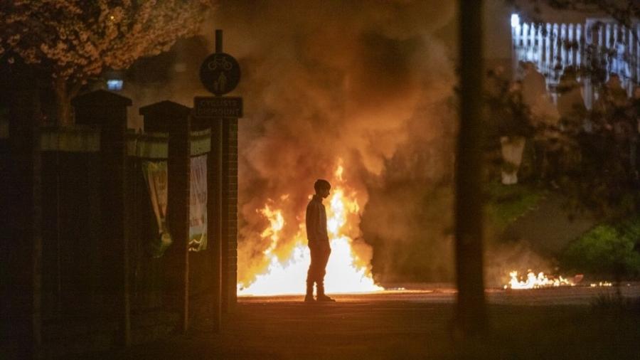 Garoto aparece próximo a chamas durante um distúrbio em Belfast, na Irlanda do Norte - 3.abr.2021 - Paul Faith/AFP