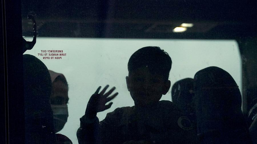Menino afegão acena de um ônibus que leva refugiados a um centro de processamento após sua chegada ao Aeroporto Internacional de Dulles, Virgínia, EUA - Kevin Lamarque/Reuters