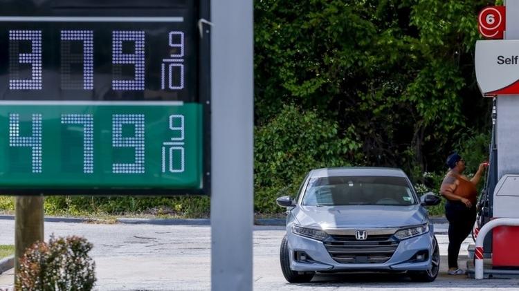 Sign with fuel prices with person filling car in background - EPA - EPA