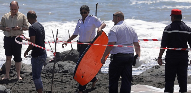 Policial retira prancha de bodyboard de vítima que morreu por ataque de tubarão - Rhicard Bouhet/ AFP