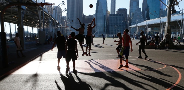 Jovens jogam basquete no parque Brooklyn Bridge, em Nova York - ALEX WROBLEWSKI/NYT