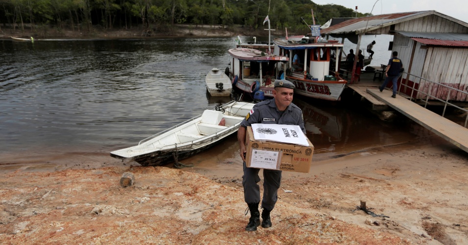 Policial carrega caixa com urna eletrônica na comunidade de Nossa Senhora de Fátima, em Manaus