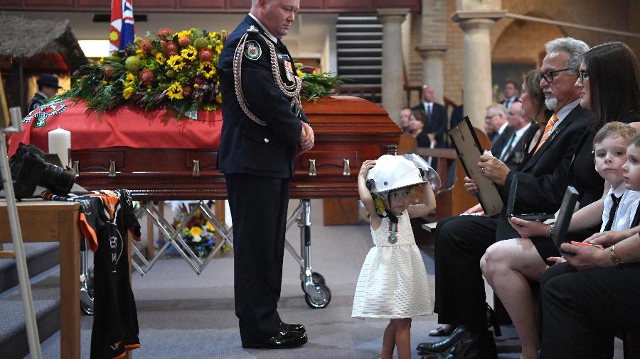 Charlotte O"Dwyer, de quase 2 anos, usa o capacete do pai, o bombeiro Andrew O"Dwyer, durante o velório dele. O"Dwyer morreu durante o combate aos incêndios na Austrália - Reuteres