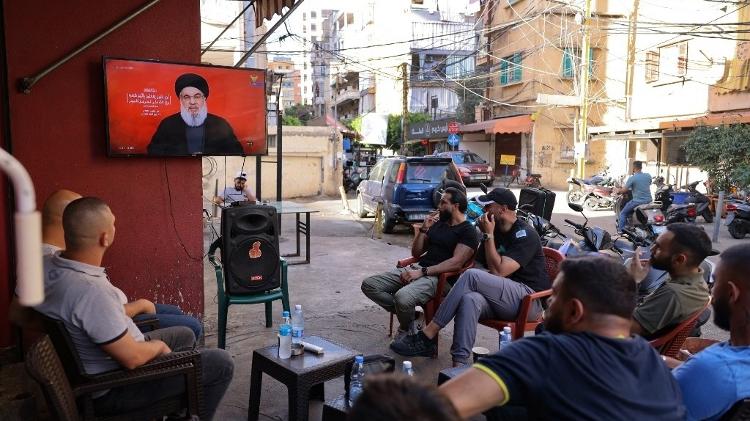 Pessoas assistem o líder do Hezbollah, Hassan Nasrallah, em um café no bairro de Shiyah, nos subúrbios ao sul de Beirute