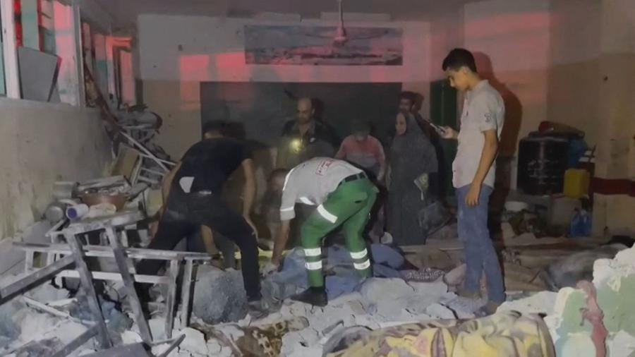 Imagem mostra equipes de resgate palestinas procurando sobreviventes na escola Osama bin Zaid, que abriga pessoas deslocadas na área de Saftawi, ao norte da cidade de Gaza