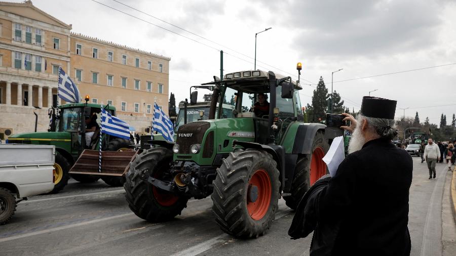 Um padre fotografa agricultores que deixam o centro da cidade de Atenas, depois de passarem a noite fora do Parlamento para pressionar por mais medidas por parte do governo sobre os altos custos de produção