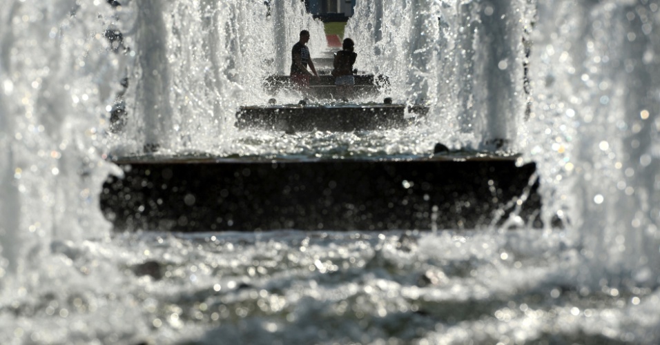 12.ago.2015 - Casal se refresca dentro de uma fonte de água no centro de Moscou, na Rússia
