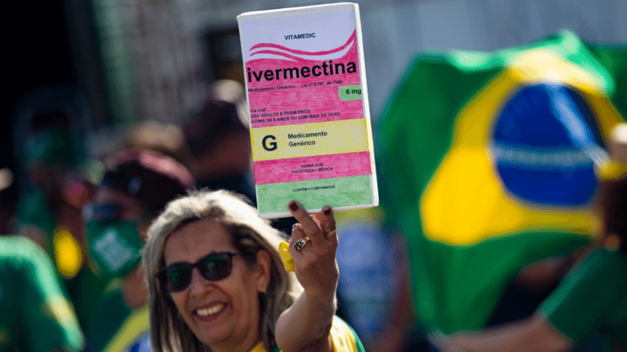 Mulher em manifestação pró-Bolsonaro segura cartaz com desenho de caixa de ivermectina - Getty Images