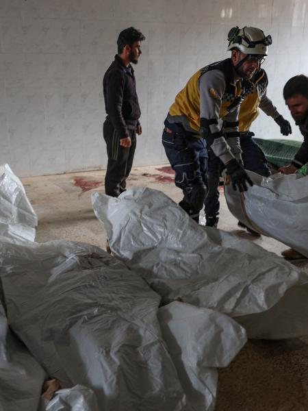 25.nov.23 - Moradores e um membro dos Capacetes Brancos sírios empilham corpos de civis mortos em um atentado a bomba do regime sírio na cidade de Kaokafin