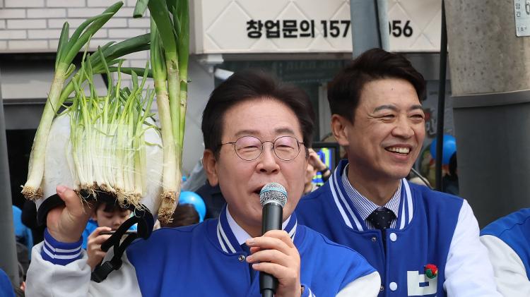 Líder da oposição do Partido Democrata da Coreia do Sul, Lee Jae-myung segura cebolinhas durante um evento de campanha